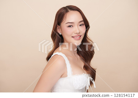 A beautiful young Asian woman with clean, fresh skin against a beige background. Skincare, facial treatment, cosmetology, beauty, and spa. An elegant portrait of an Asian woman. A beautiful young Asian woman with clean, fresh skin against a beige background. Skincare, facial treatment, cosmetology, beauty, and spa. An elegant portrait of an Asian woman. 128154117
