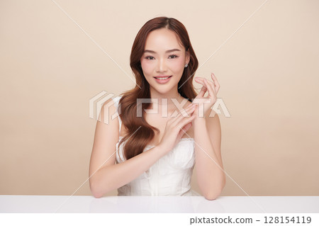 A beautiful young Asian woman with clean, fresh skin against a beige background. Skincare, facial treatment, cosmetology, beauty, and spa. An elegant portrait of an Asian woman. A beautiful young Asian woman with clean, fresh skin against a beige background. Skincare, facial treatment, cosmetology, beauty, and spa. An elegant portrait of an Asian woman. 128154119