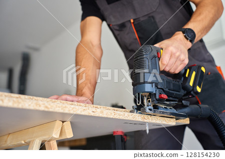 Man using jigsaw in workshop 128154230
