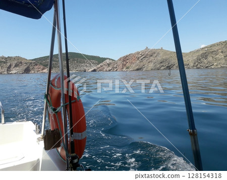 Peaceful Ocean Voyage with Reflective Waters and Distant Rocky Mountain Ranges on a Sunny Day 128154318