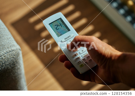 Air conditioner remote control in hand, close up 128154356
