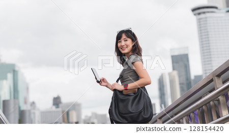 Happy young southeast asian woman teenager blogger using smartphone for searching travel guide. World explorer with local cultural experience on Chao Phraya river in Bangkok Asia tourism concept 128154420