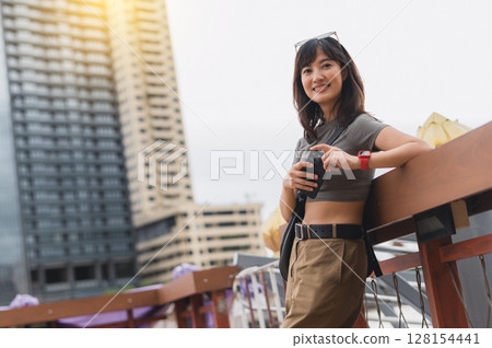 Happy solo Southeast Asian woman teenager blogger on world travel tourism wait for boat to express local cultural experience on Chao Phraya river in Bangkok Thailand concept for asia explorer 128154441