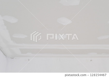 Inside building undergoing interior renovation gypsum board ceiling with electrical wire installation shows smooth edges and areas ready for plastering creating smooth finish 128154467