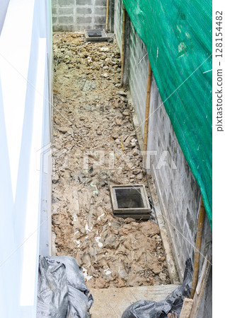 High angle view of messy passage during major house renovation. dug up ground and rubble show demanding process of home improvement and exterior construction work 128154482