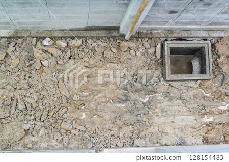 Unfinished floor during major house renovation project. ground shows exposed soil rock and new drain installation for construction site feeling of progress Unfinished floor during major house renovation project. ground shows exposed soil rock and new drain installation for construction site feeling of progress 128154483