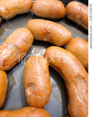 A close up of golden brown dinner sausages arranged in a baking pan, showcasing their soft, fluffy texture and slightly glossy surface A close up of golden brown dinner sausages arranged in a baking pan, showcasing their soft, fluffy texture and slightly glossy surface 128155676