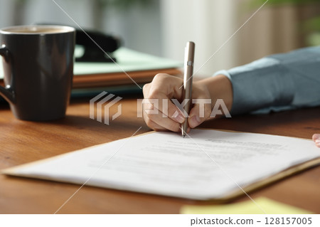 Businesswoman hands signing contract on wooden table Businesswoman hands signing contract on wooden table 128157005