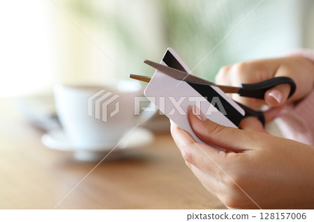Woman hand destroying credit card cutting with scissors Woman hand destroying credit card cutting with scissors 128157006