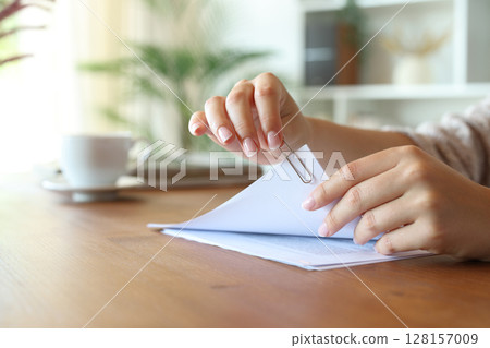 Woman hand putting a paper clip on document sheets at home 128157009