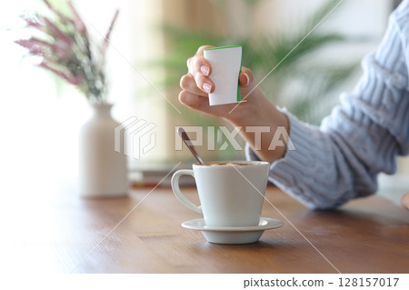Woman hand throwing saccharin pill on coffee cup at home Woman hand throwing saccharin pill on coffee cup at home 128157017