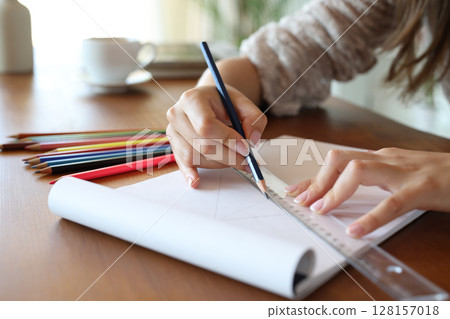Woman hand using pencil and ruler to draw on notebook Woman hand using pencil and ruler to draw on notebook 128157018