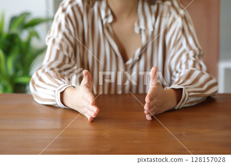Woman hands gesturing measurement on a wooden table Woman hands gesturing measurement on a wooden table 128157028