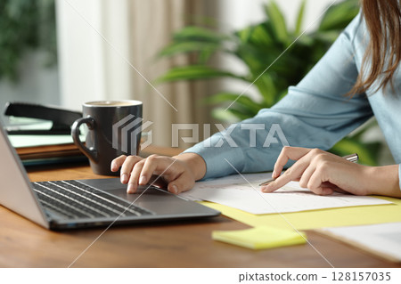 Woman hands working checking documents and using laptop Woman hands working checking documents and using laptop 128157035