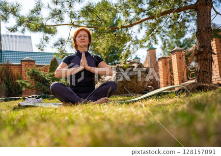 Woman meditating outdoors in a peaceful park setting during her morning routine. Mindfulness, mental balance, and emotional self-care. Woman meditating outdoors in a peaceful park setting during her morning routine. Mindfulness, mental balance, and emotional self-care. 128157091