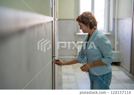 Woman opening the door to her office at the start of the workday. Entry, new beginning, and everyday professional routine. 128157118