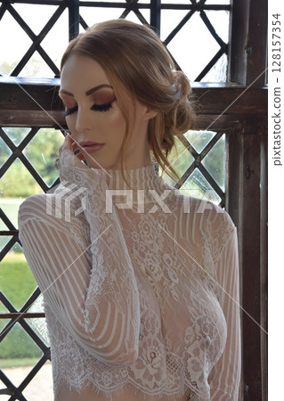 Beautiful, redheaded girl dressed in lace, posing in rooms of an old Manor House 128157354