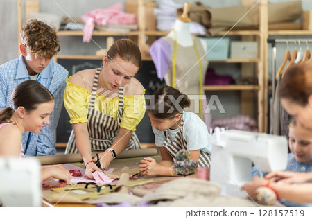 Children students cut fabric, work with material, preparatory work. Children students cut fabric, work with material, preparatory work. 128157519