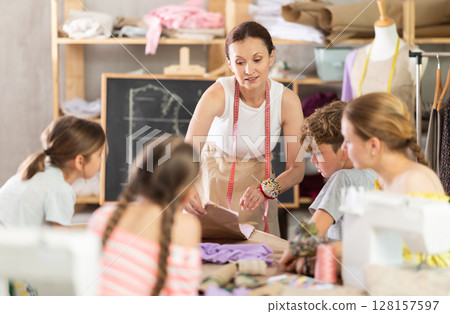 Teacher showing kids pattern work in school sewing class 128157597