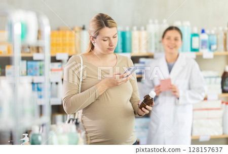 Pregnant woman scanning syrup bottle with phone to check ingredients online 128157637