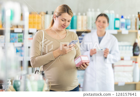 Pregnant woman buyer scans pills qr code with woman pharmacist Pregnant woman buyer scans pills qr code with woman pharmacist 128157641