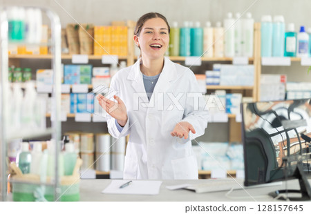 Friendly female pharmacist inviting customer to pharmacy 128157645