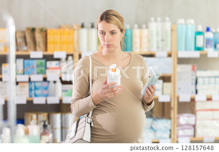 Pregnant woman choosing cream in drugstore Pregnant woman choosing cream in drugstore 128157648
