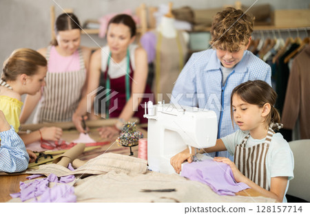 Girl child watches female classmates sew and creating clothes Girl child watches female classmates sew and creating clothes 128157714