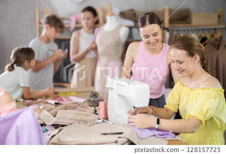 Girl child watches female classmates sew and creating clothes 128157725