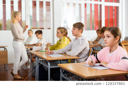 Teenagers sitting at desks in classroom during lesson Teenagers sitting at desks in classroom during lesson 128157801