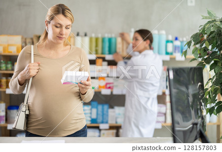 Pregnant woman chooses pills at pharmacy 128157803