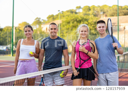 Team of men and women after playing tennis on tennis court Team of men and women after playing tennis on tennis court 128157939