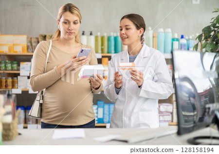 Expecting woman comparing supplements using phone at drugstore Expecting woman comparing supplements using phone at drugstore 128158194