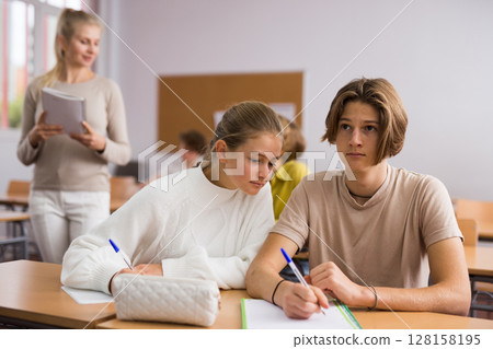 Teenagers doing tasks during lesson in school Teenagers doing tasks during lesson in school 128158195