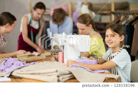 Girl child sews during practical lesson at school of young fashion designers and tailors Girl child sews during practical lesson at school of young fashion designers and tailors 128158196
