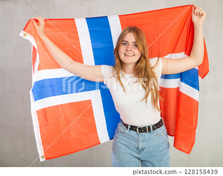 Portrait of young female supporter of the Norway team wearing national flag 128158439