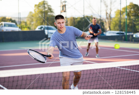 Sports active man during friendly doubles couple match. Two men playing together tennis 128158445
