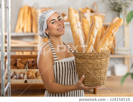 Young female seller with baguettes in basket 128158510