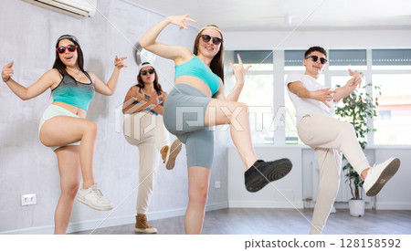 Group of young women and young guy in sunglasses dancing hip hop 128158592