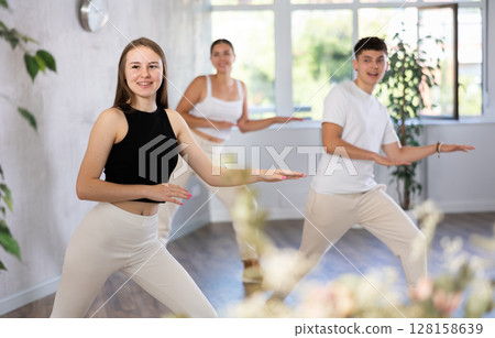 Group of happy young sports people exercising dancing in modern studio 128158639