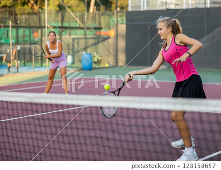 Tennis game - girl actively kicks the ball during tennis game Tennis game - girl actively kicks the ball during tennis game 128158657