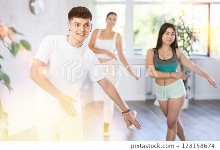 Group of energetic girls and guys learning dance at class 128158674