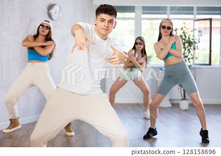 Young b-boy dancing with group of friends in dance studio 128158696
