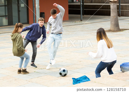 Cheerful teenagers are jogning with ball on street Cheerful teenagers are jogning with ball on street 128158710