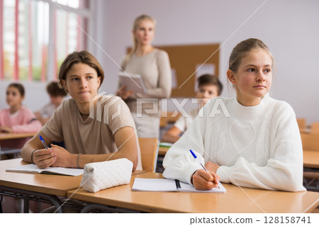 Teenagers doing tasks during lesson in school Teenagers doing tasks during lesson in school 128158741