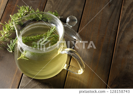 Teapot with rosemary leaves and herbal tea Teapot with rosemary leaves and herbal tea 128158743