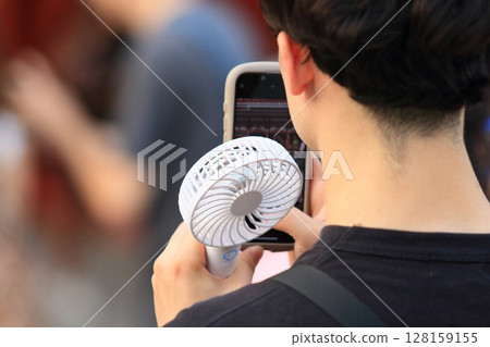 A man walking with a handheld fan A man walking with a handheld fan 128159155