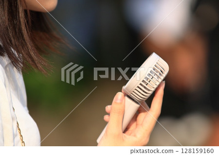 A woman walking with a handheld fan A woman walking with a handheld fan 128159160