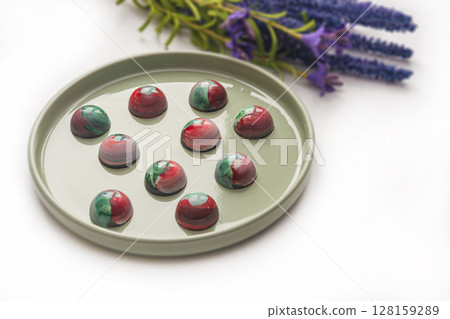 Collectible handmade tempered chocolate sweets with a glossy painted body on a round plate Collectible handmade tempered chocolate sweets with a glossy painted body on a round plate 128159289
