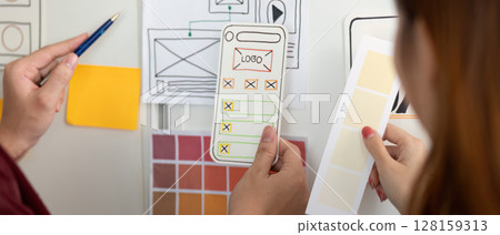 UX and UI Design. Hands holding design mockups and color palettes for mobile app. 128159313